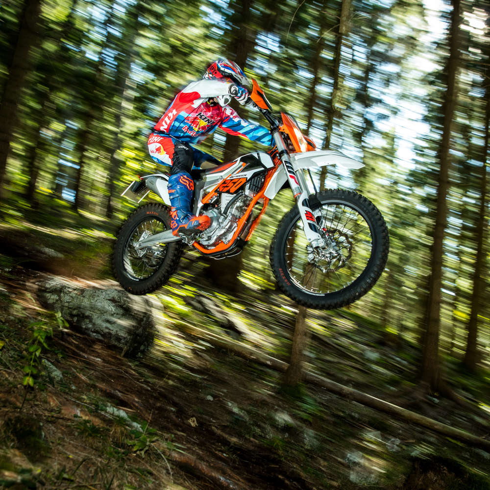 KTM Offroadmotorrad Freeride 250 springt von links nach rechts von einem Felsen mitten im Wald